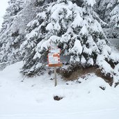 schneelandschaft bei karerpass wanderweg wald wegweiser