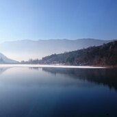 Montiggler See halb zugefroren Schnee
