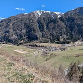 aussicht vom weg ins tal hinunter bis auf die schneebedeckten berge