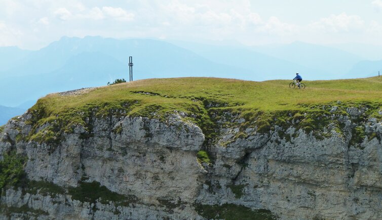 radfahrer am monte roen gipfelkreuz